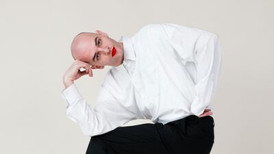 Een rode lippenstift en een witte blouse zit in een pose op een stoel.