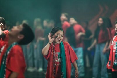 Kind danst vrolijk in rood-groen-zwarte supportersstijl tijdens een podiumoptreden